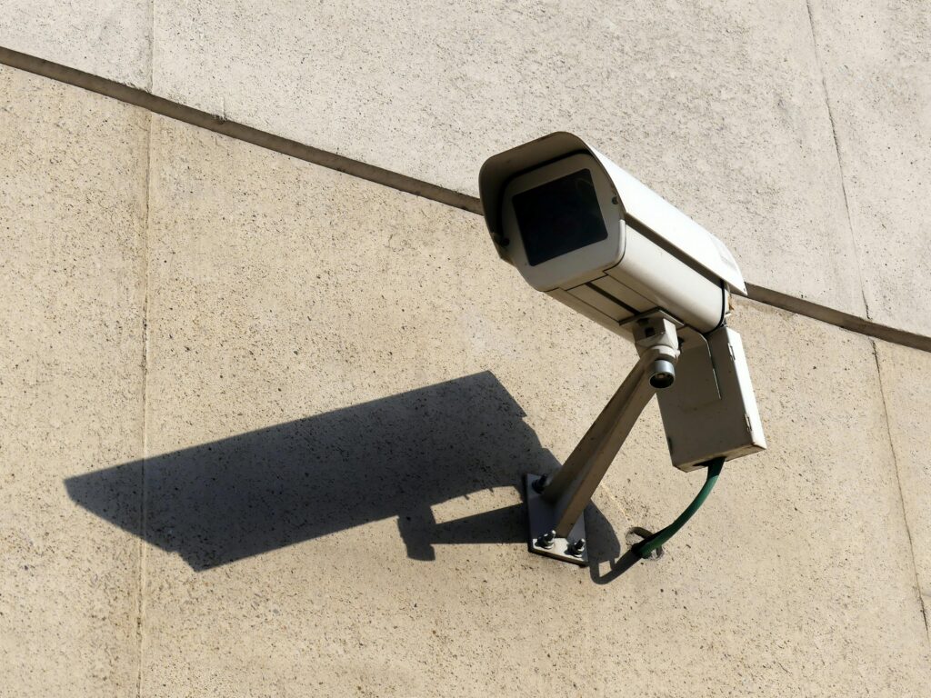 Modern surveillance camera mounted on a concrete wall casting a shadow.